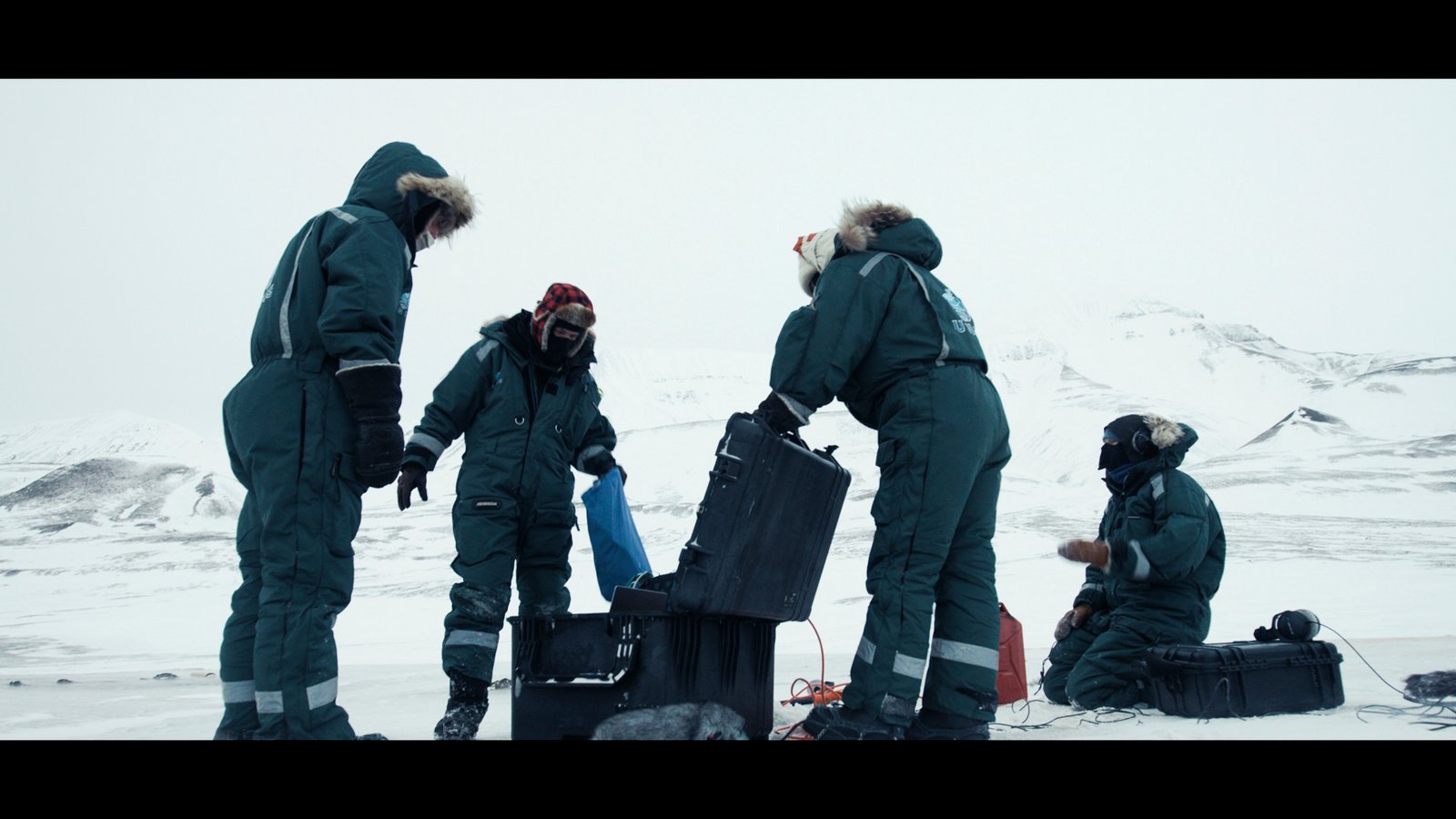 Plan large, des hommes et des femmes en combinaisons posent des instruments d'écoute dans la glace