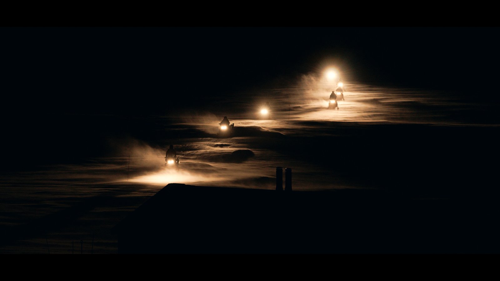 Des phares de motoneiges éclairent la nuit