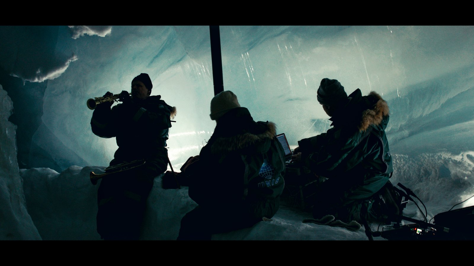 Plan large, des musiciens jouent dans une grotte de glace